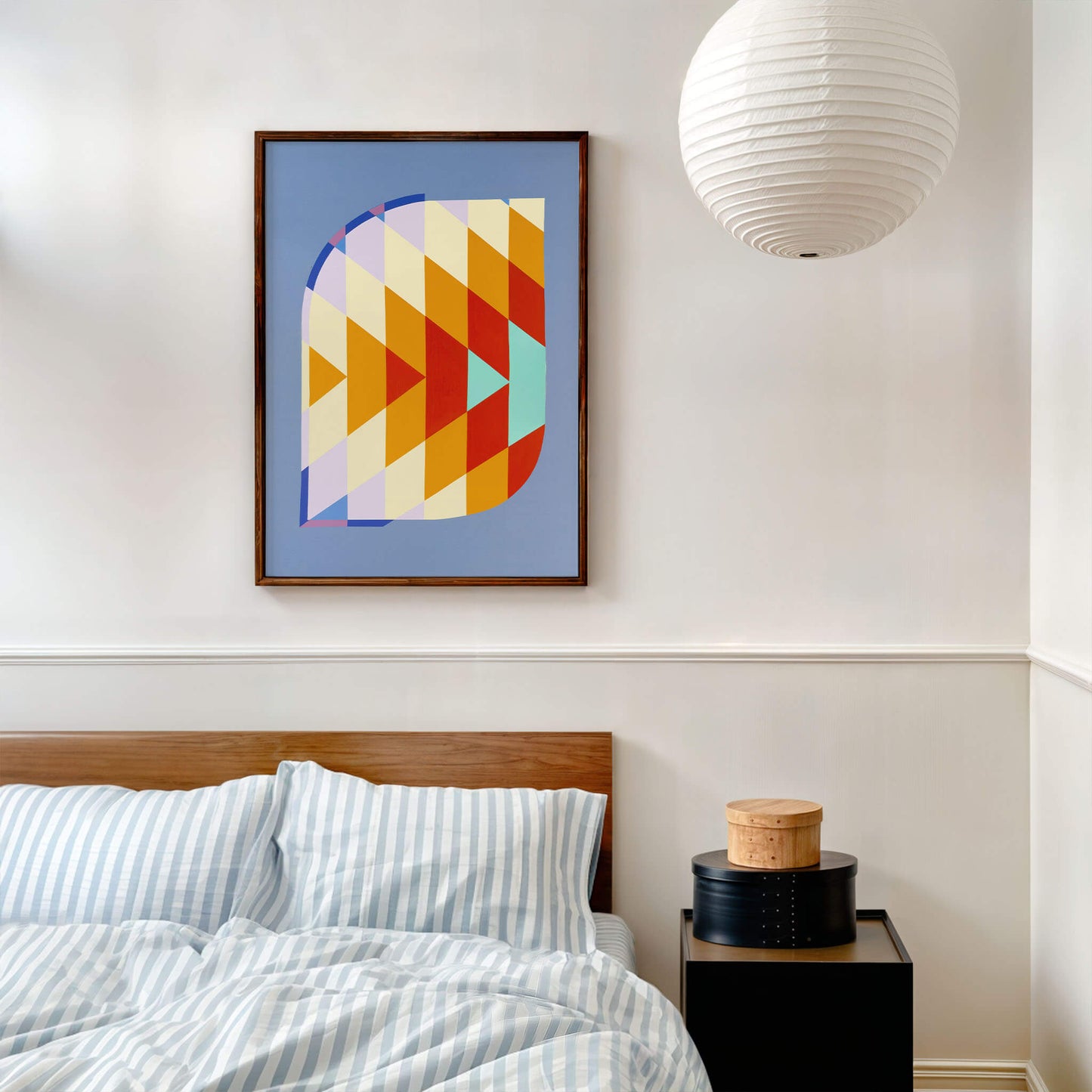 Abstract coloured print above a modern bed and beside table. Sphreical paper light hanging from the ceiling.