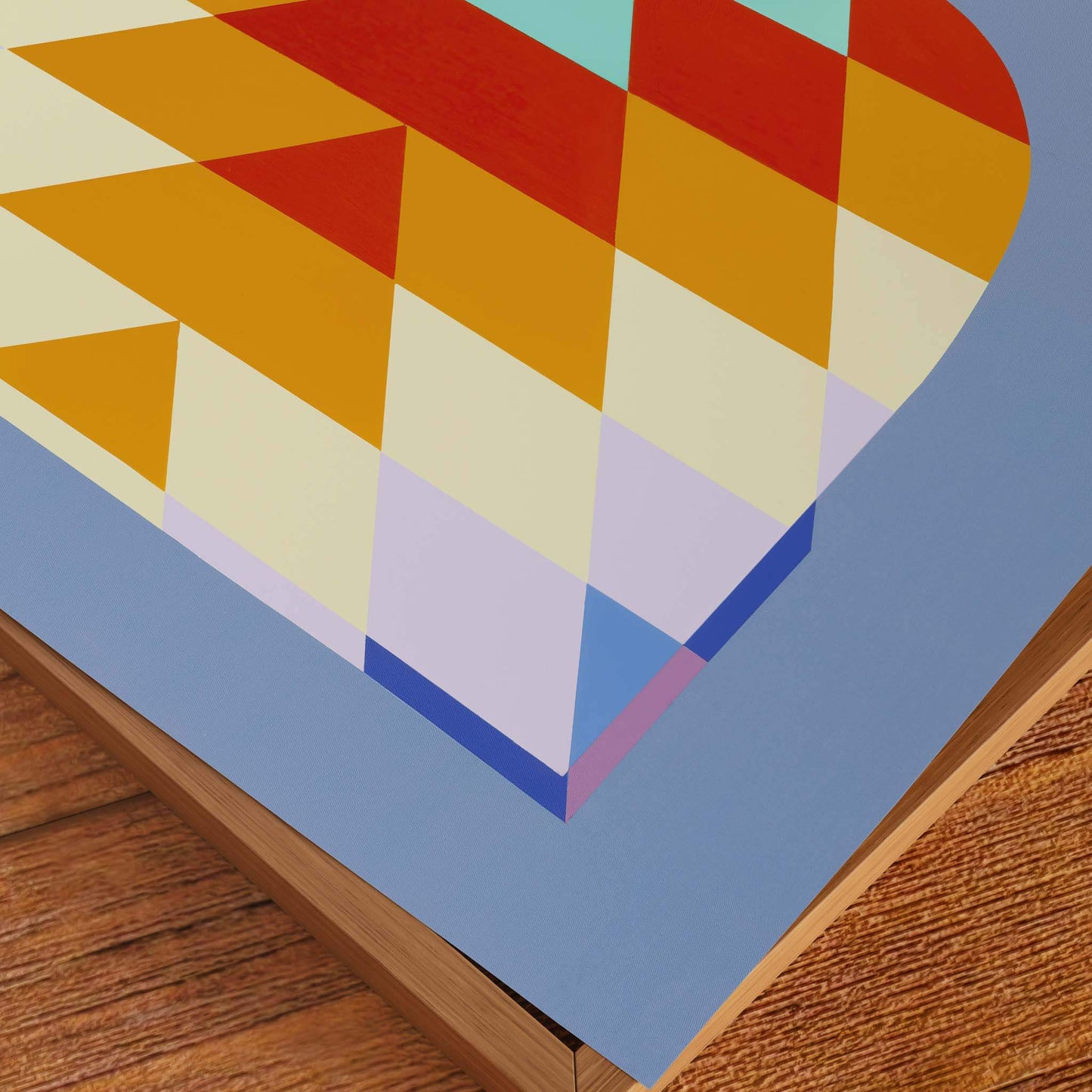 Close up of a coloured art print on top of a frame and wooden tabletop.