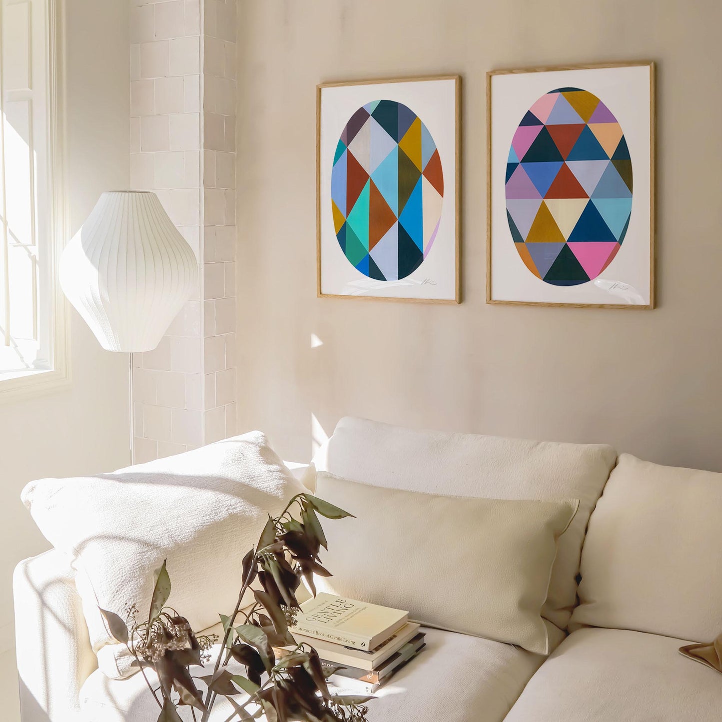 Living room with a white sofa, decorative pillows, and two colourful abstract art prints on the wall.