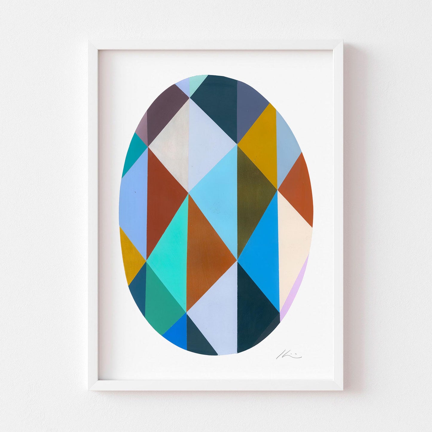 Framed geometric art print with multicoloured shapes on a white wall.