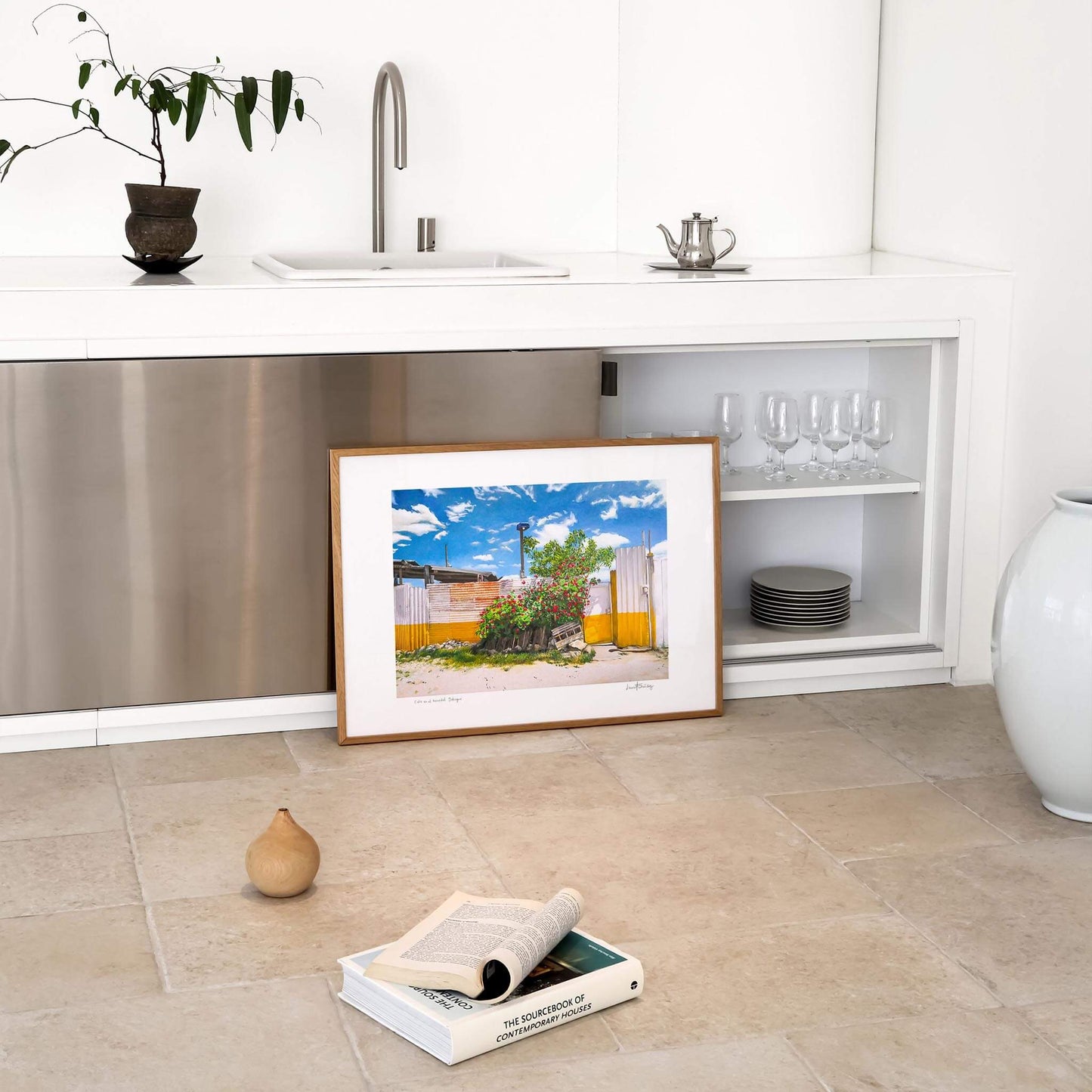 Modern landscape art print framed in oak propped against a modern kitchen unit.