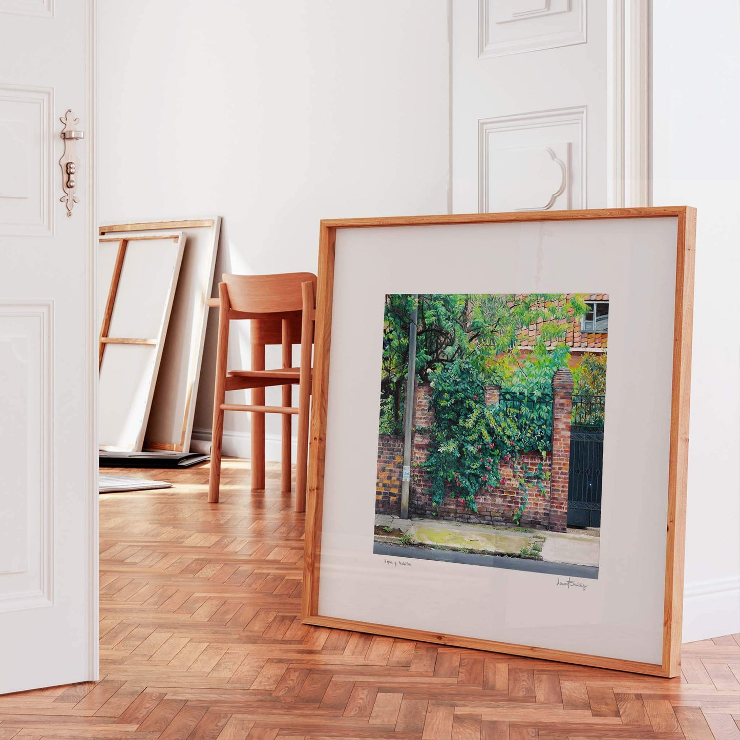 Landscape art print in an oak frame propped against a doorway.