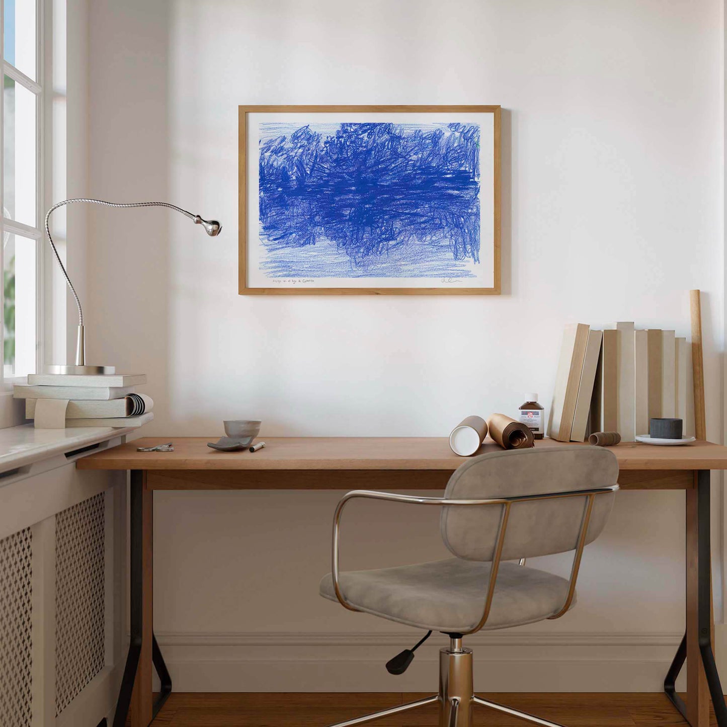 Framed blue landscape art print in a neutral home office.