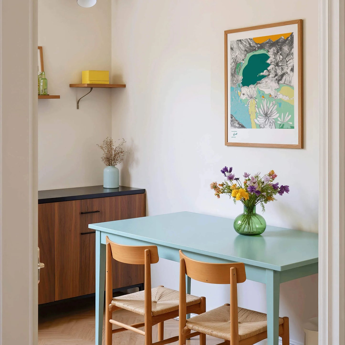 Dining area with a light blue table, wooden chairs, and a colorful abstract painting on the wall.