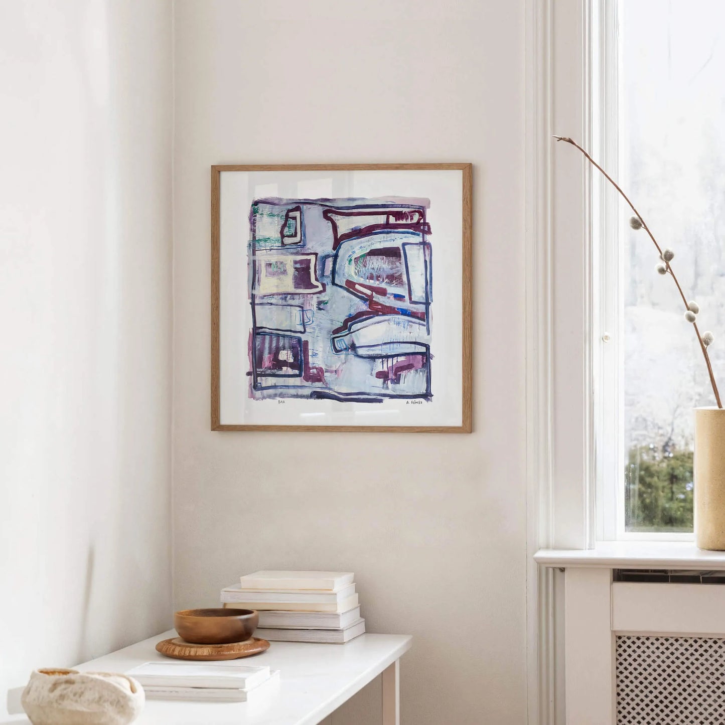 Abstract artwork on a wall in a room with a table and window.