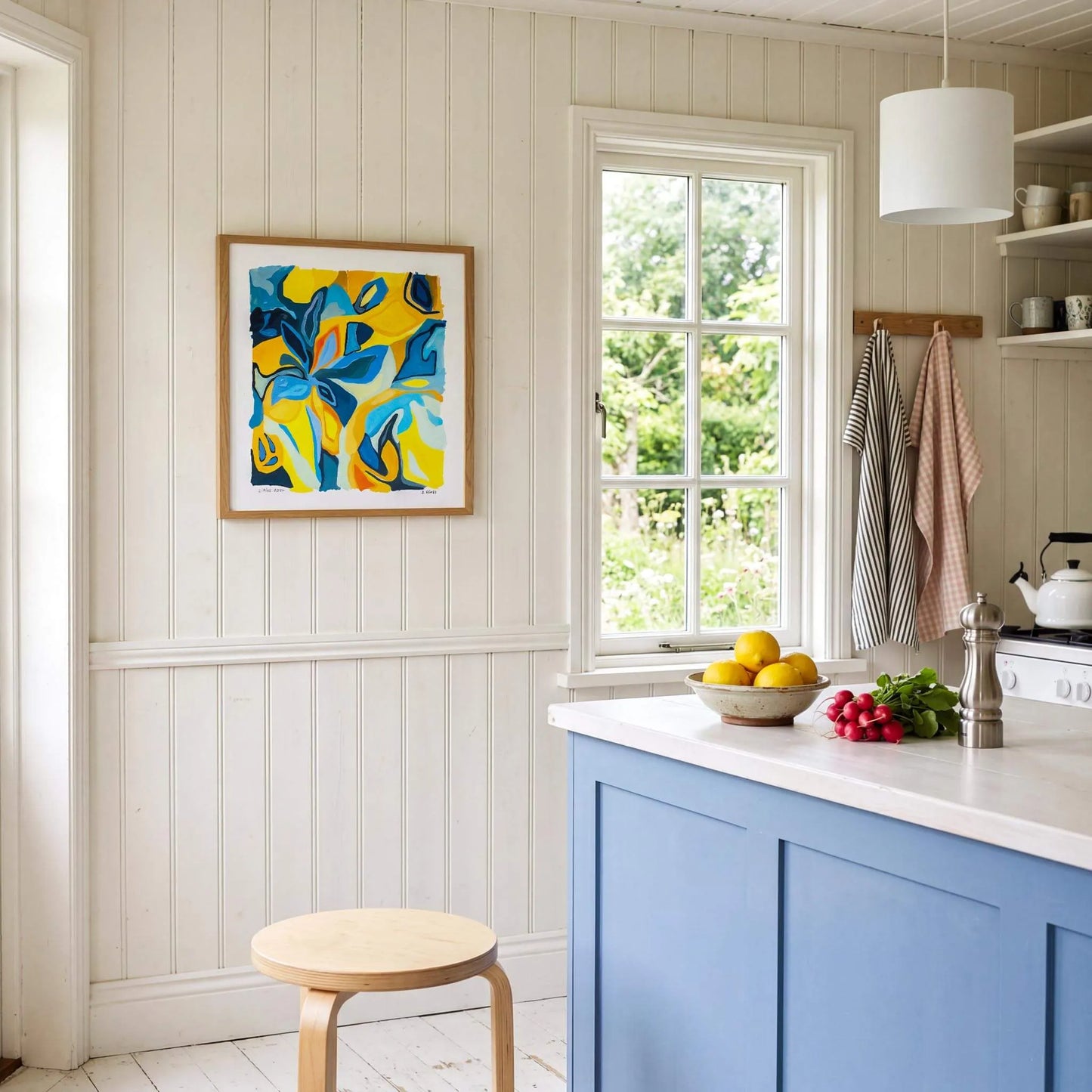 Kitchen interior with blue cabinets, a window, and a colorful abstract painting on the wall.