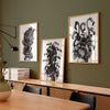 Set of three monochrome wall art prints on a dark green wall in an office.