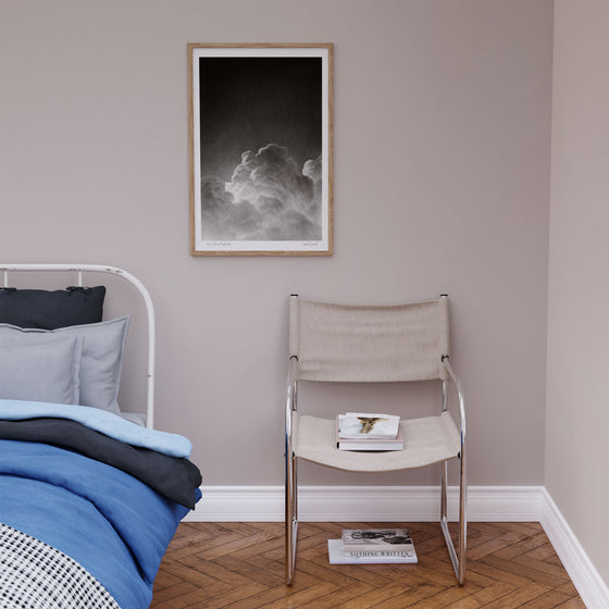 Framed black and white wall art print of a cloud in a neutral bedroom.
