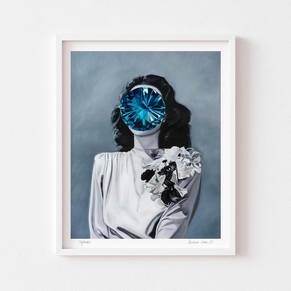 
                  
                    Contemporary wall art print of a woman with a blue gem over her face framed in white.
                  
                