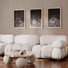 Set of three black and white wall art prints of clouds in a modern living room.