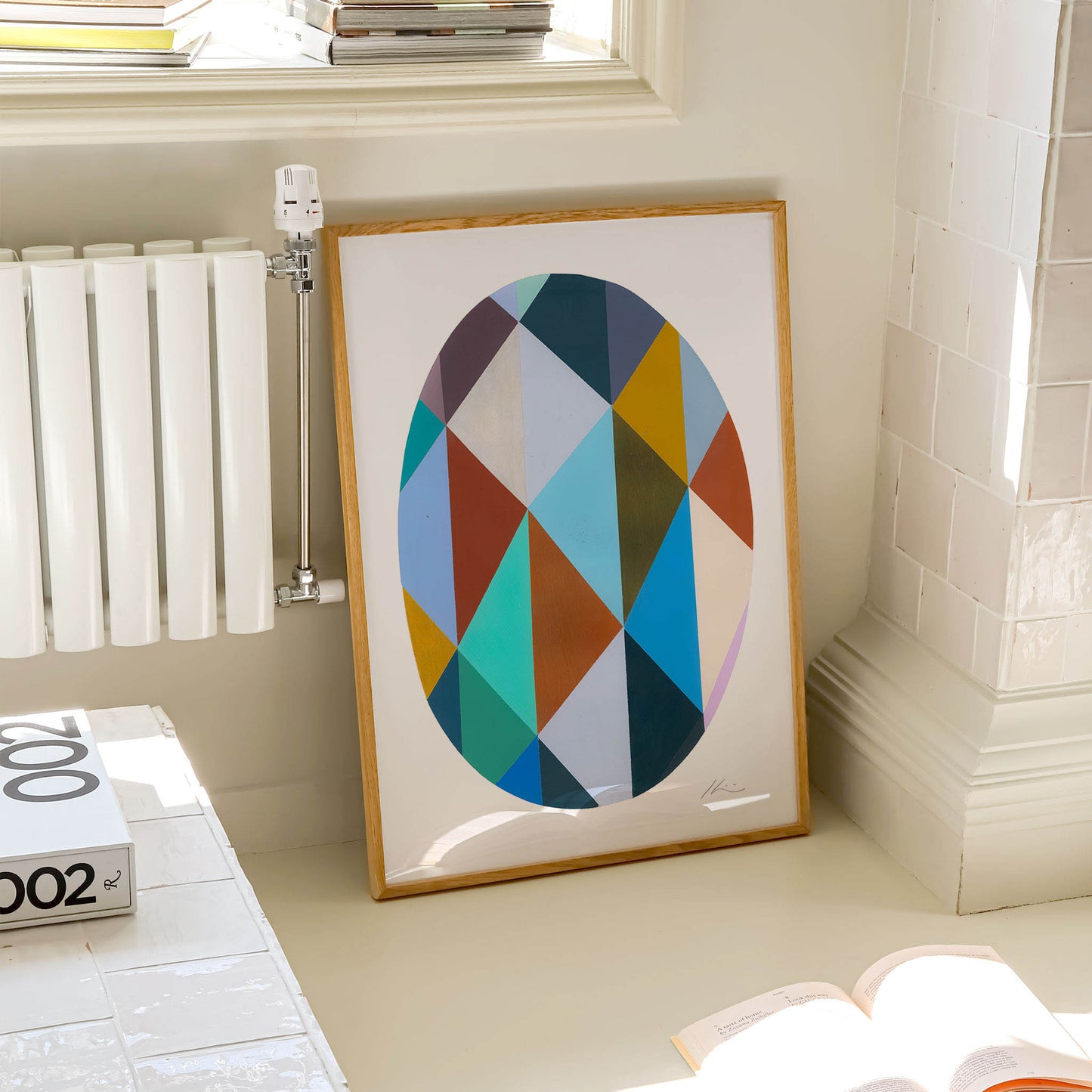 Framed geometric art print  propped against a wall in a modern living room.