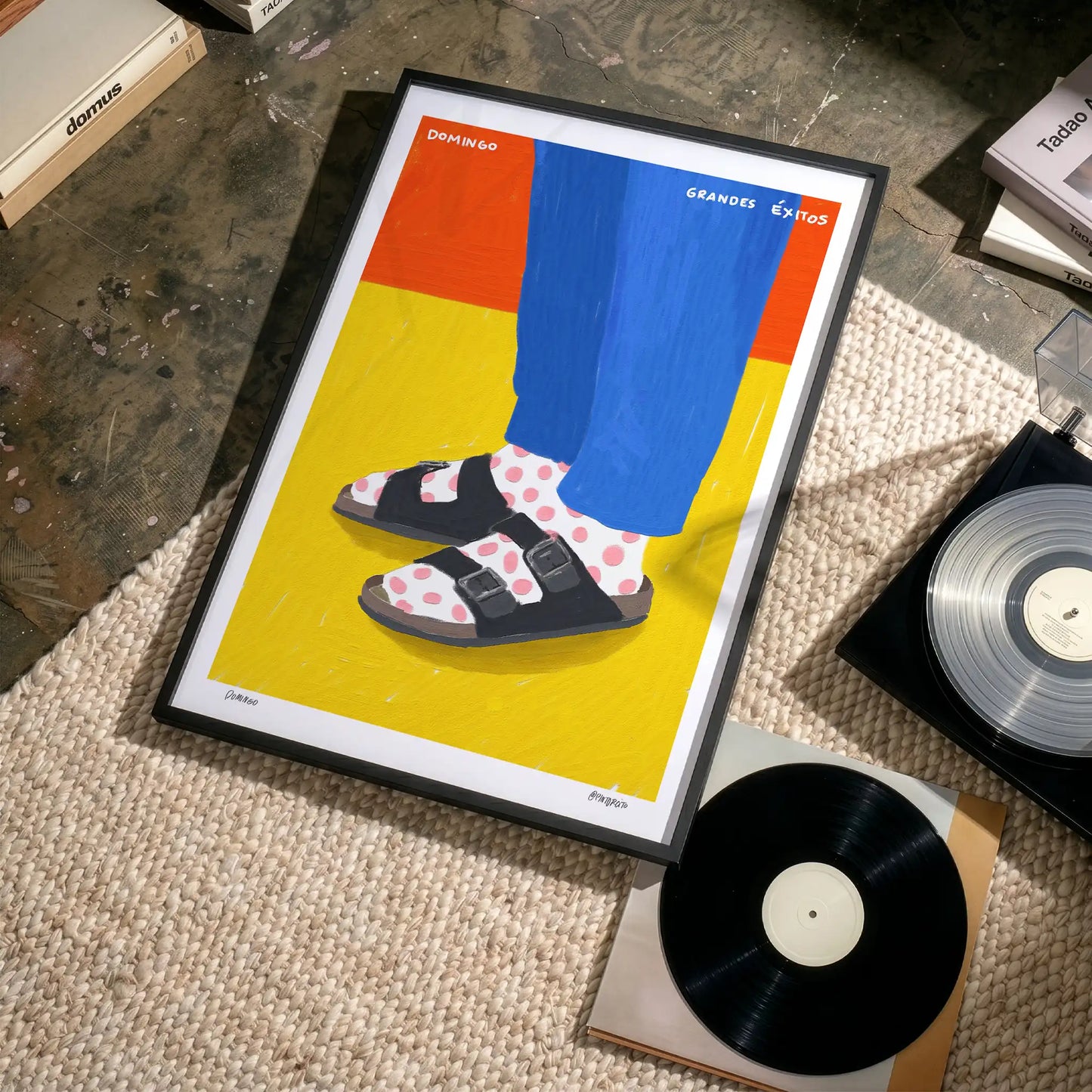 Framed print of a person wearing Birkenstock sandals and bright blue pants on a rug with records and boxes.