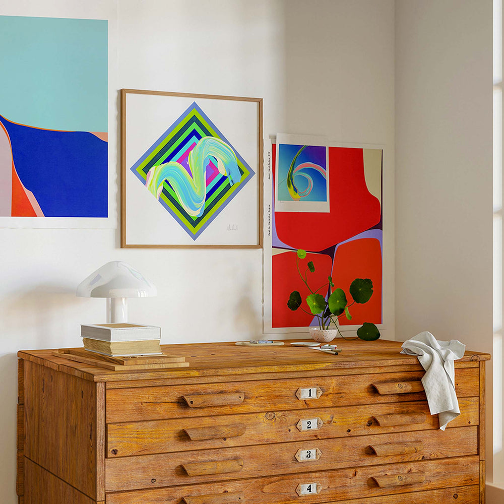 
                  
                    Bold and colourful art prints in a contemporary interior with a wooden plan chest.
                  
                