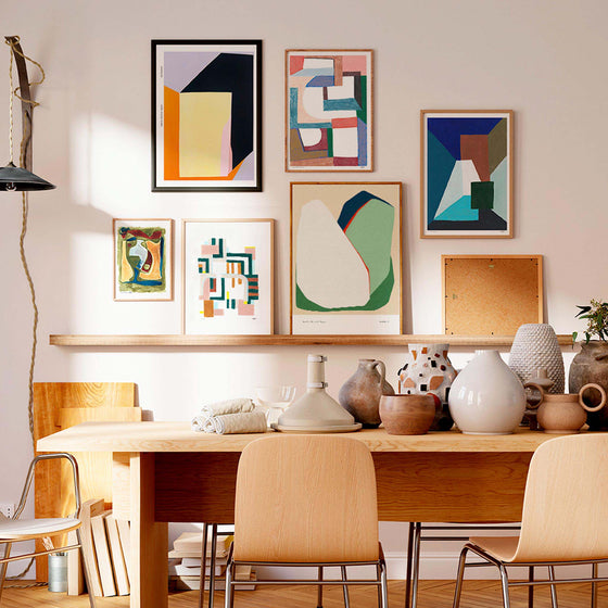 Gallery wall of abstract art prints in a neutral dining room and living space.