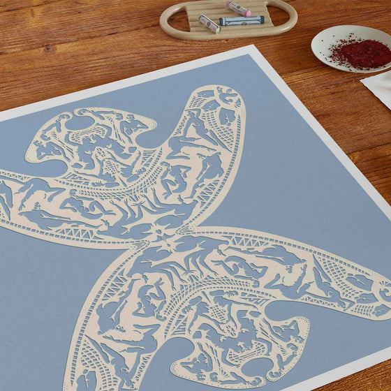 Unframed light blue papercut art print on a desk in a home office.