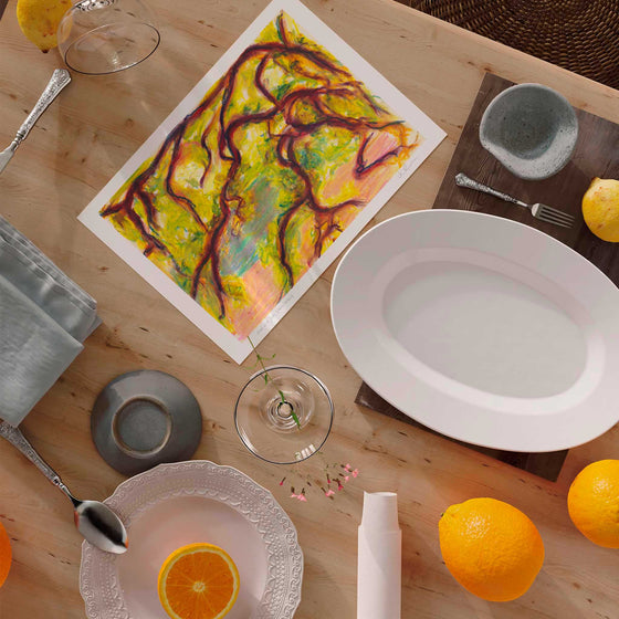 Modern botanical wall art print, unframed on a wooden kitchen table surrounded by plates and oranges.