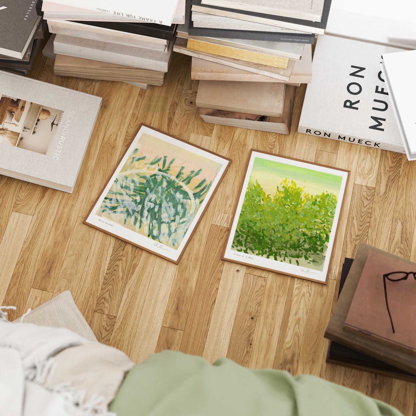 Art prints on a wooden floor with books and a magazine.