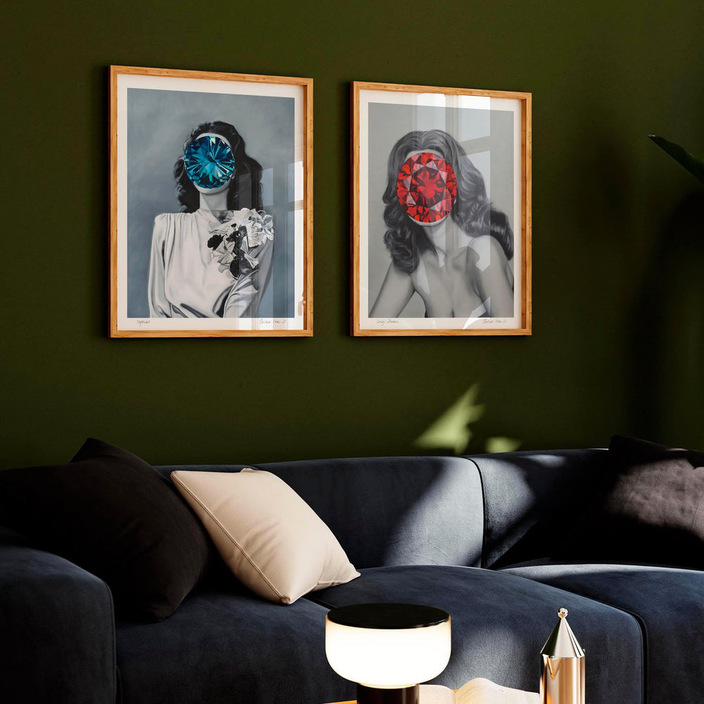 
                  
                    Pair of framed art prints of women with red and blue jewels covering their faces framed against a dark wall in a living room.
                  
                