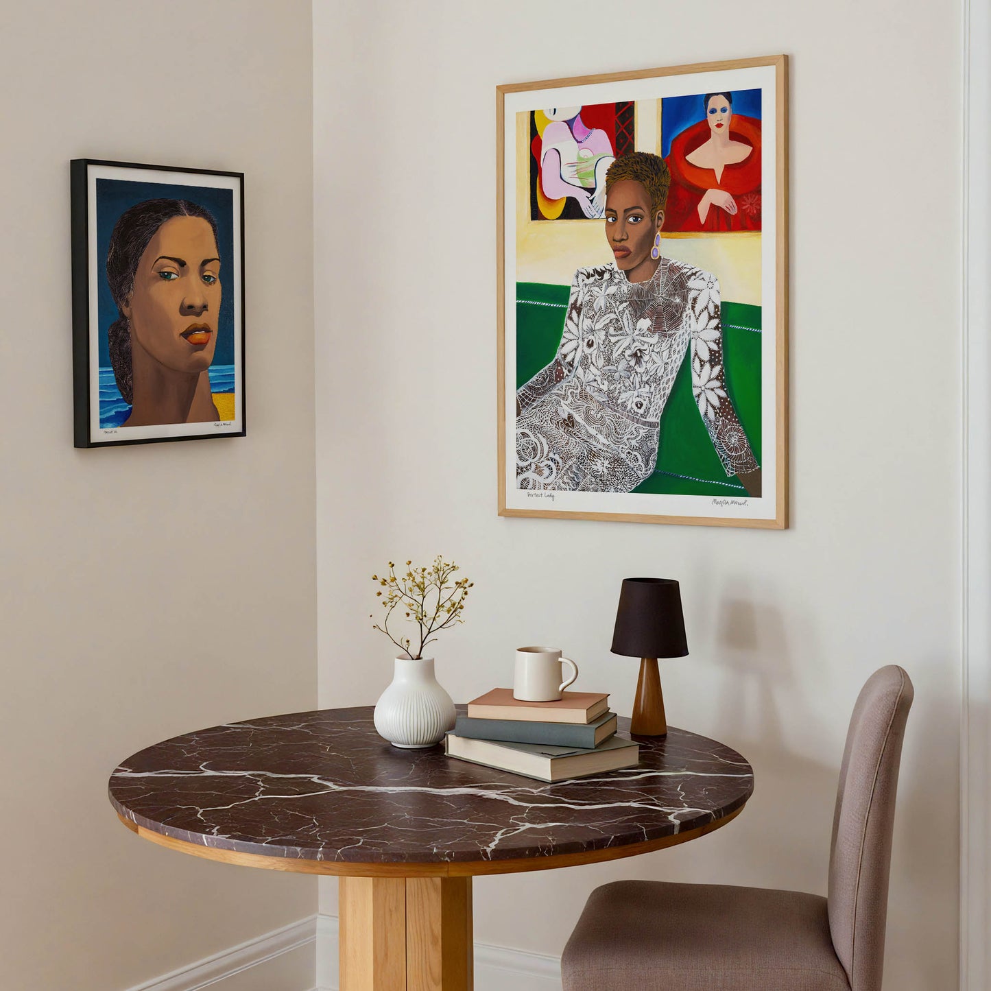 Round marble table with books, a cup and a vase in a room with framed artwork on the wall.