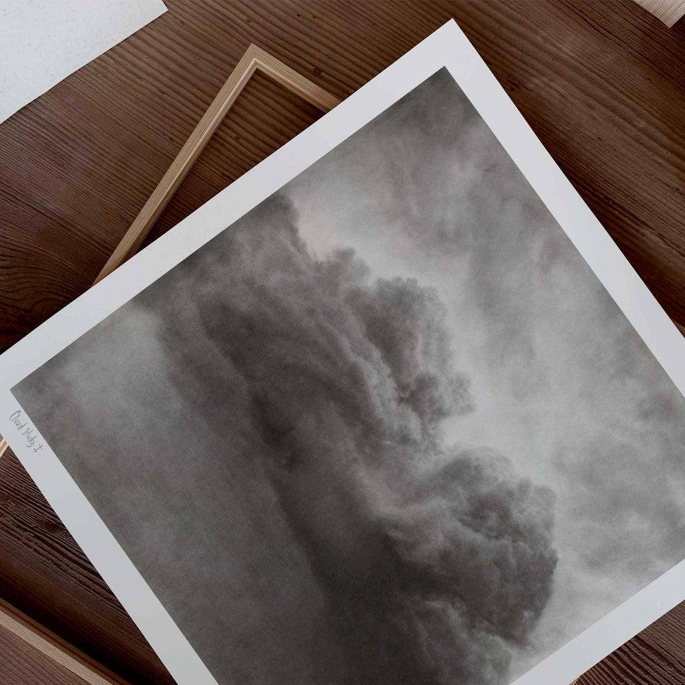 
                  
                    Unframed black and white wall art print of a cloud on a wooden desk.
                  
                