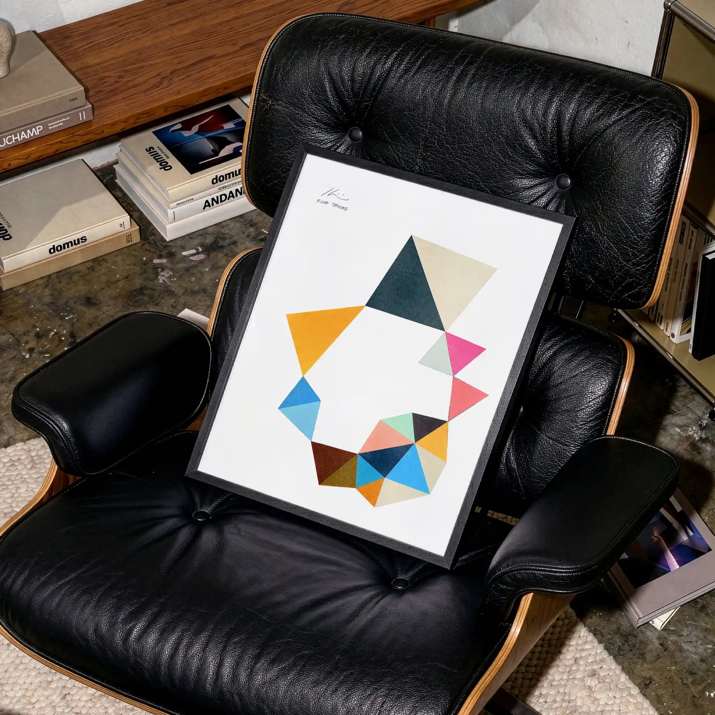 Framed abstarct art print on a black leather armchair in a contemporary living room.