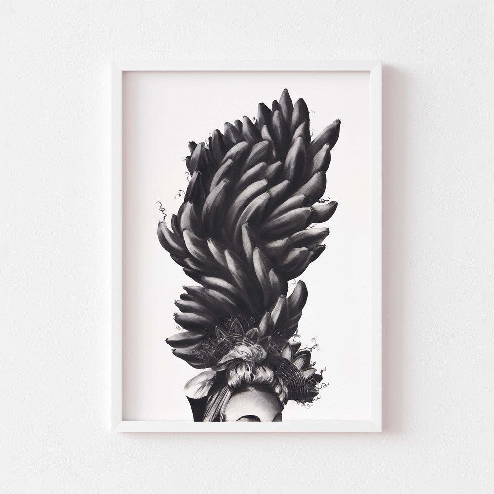 
                  
                    Black and white wall art print of a women wearing a banana headdress framed in white.
                  
                