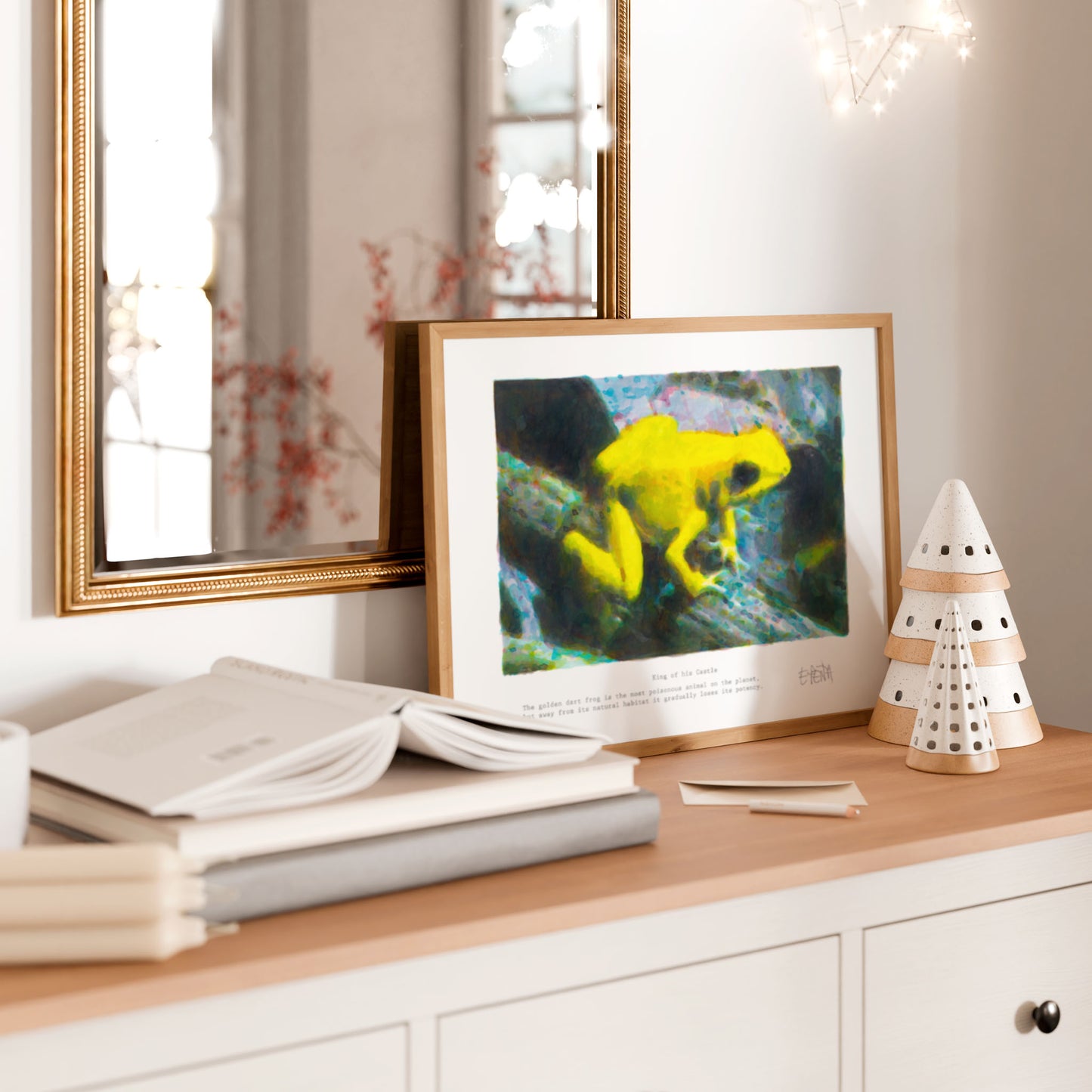 Framed artwork of a yellow frog on a wooden surface with books and decorative items.