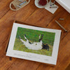 Unframed art print of a fainting goat on a desk in a home studio.